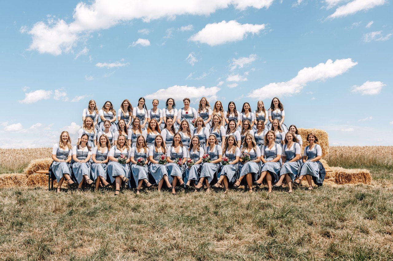 Gruppenbild der Festdamen in hellblauen Dirndln vor einem Kornfeld