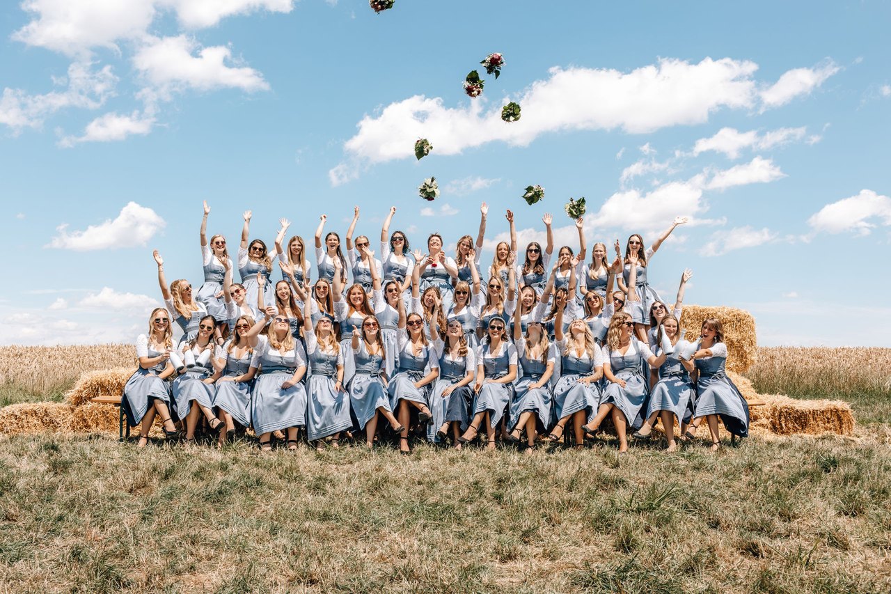 Festdamen jubeln und werfen Blumensträuße in den Himmel